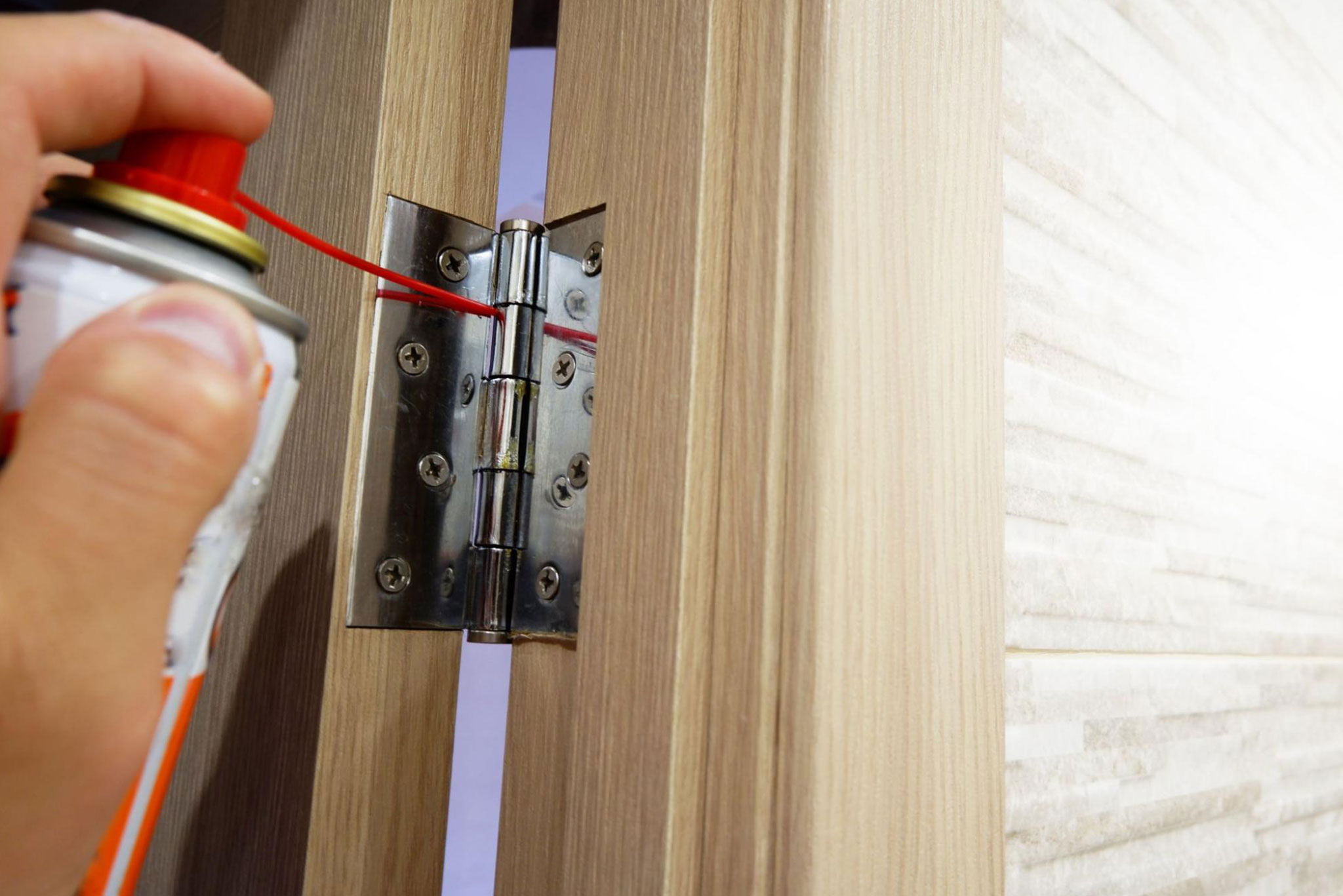 Close-up of someone lubricating the door hinges