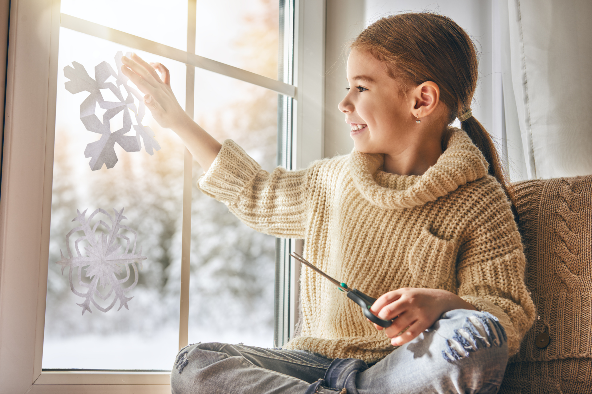 A child pasting snowflake cutouts on a window in the winter