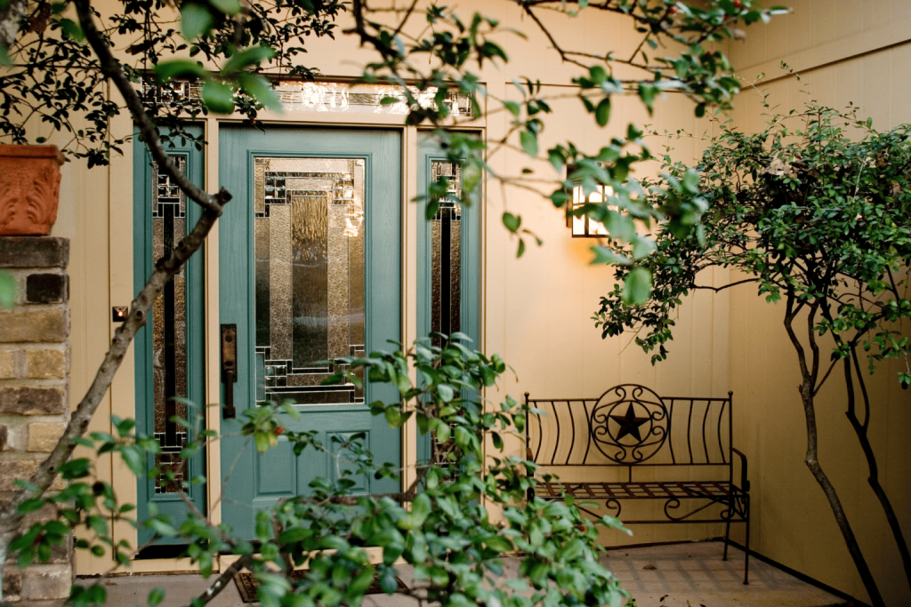 a turquoise entry door with glass panes and framed with foliage