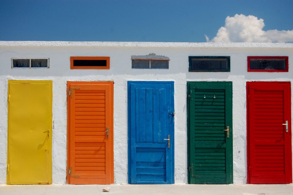  A row of multi-coloured doors against a white wall 
