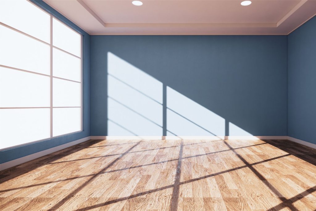 A large floor-to-ceiling window letting in natural light inside an empty blue room