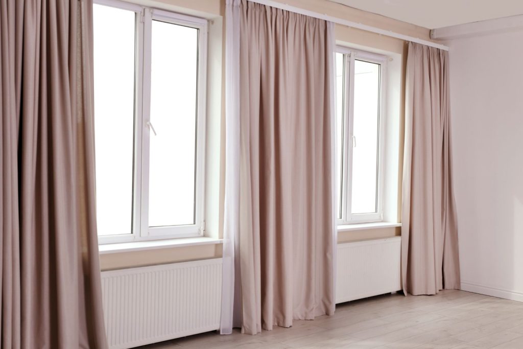 Two double casement windows with thin casement window trims and rose-coloured curtains between them 