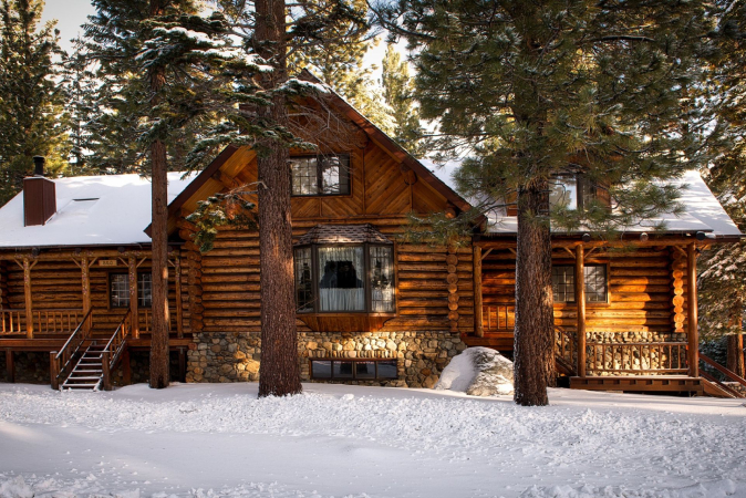 A winter log cabin with bay windows and fixed windows