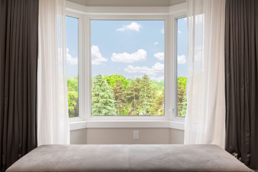 A bay window area in the bedroom framed with floor-to-ceiling curtains 