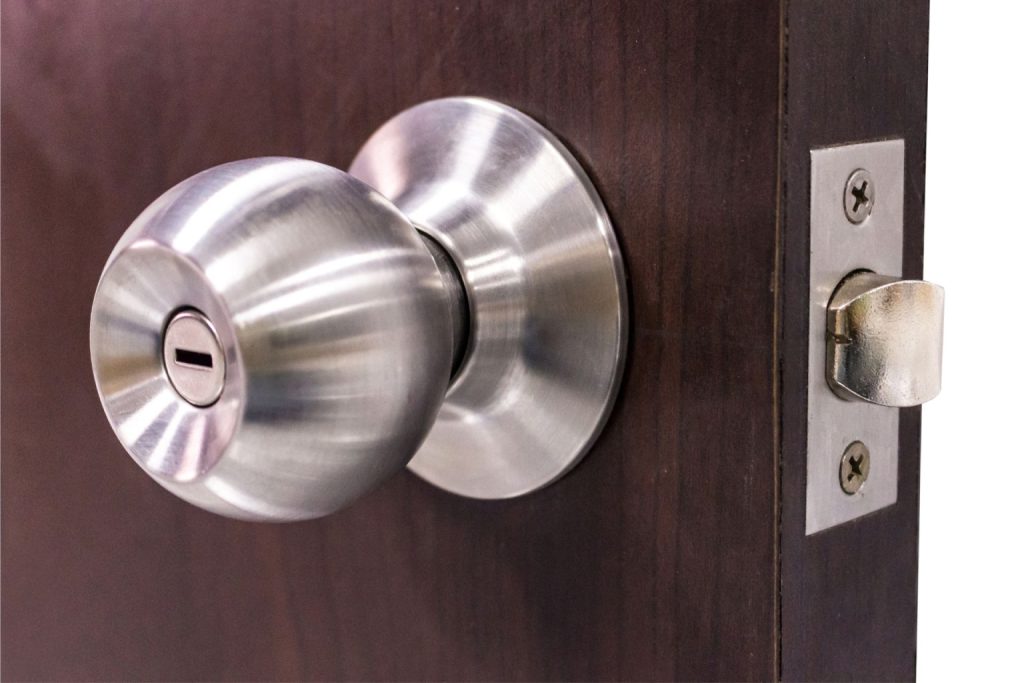 A wooden door with a monochrome door knob and lock
