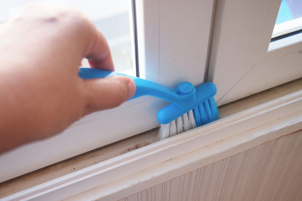 A person brushing window tracks