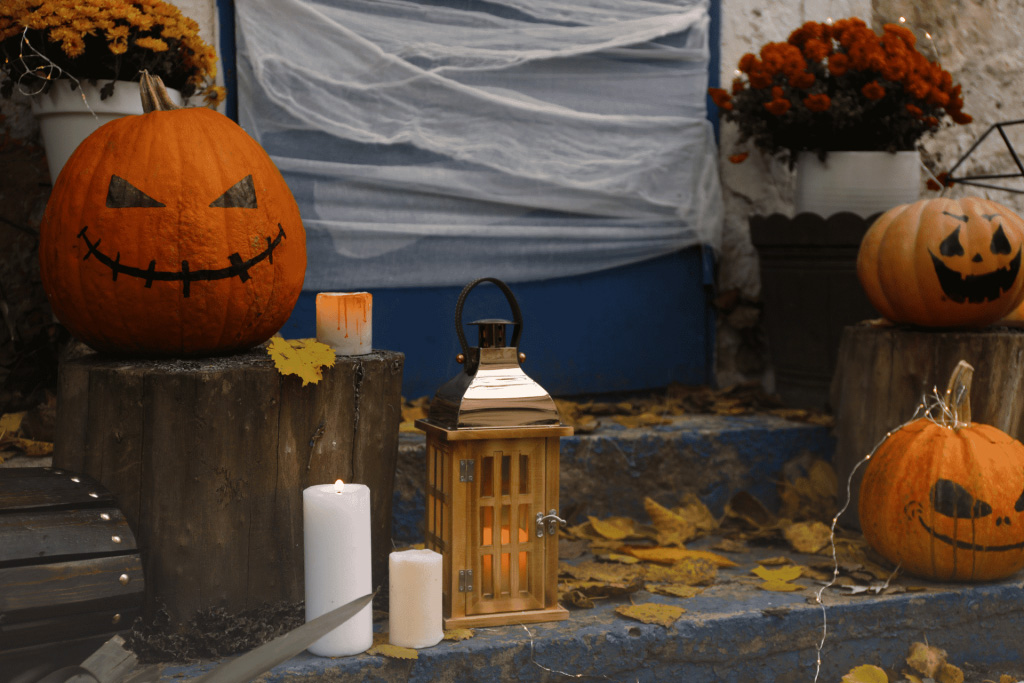 Jack-o-lanterns, candles, and a lamp on the front porch steps