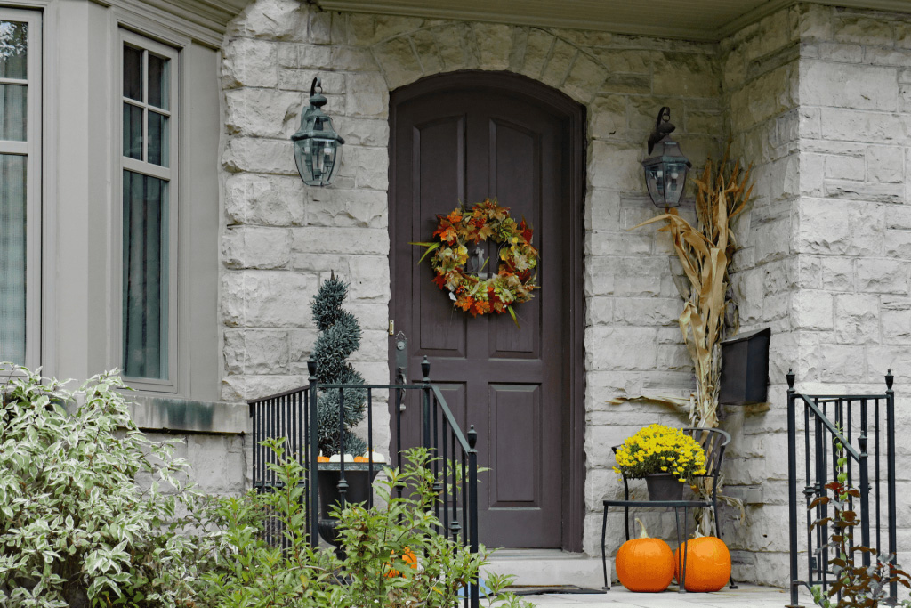 A classic brown door with a fall wreath attached to it.