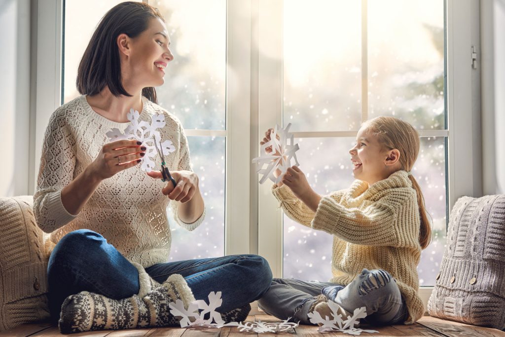 Family making paper snowflakes by the window