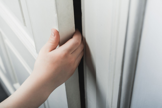 A child’s hand wedged between a closing door and the frame