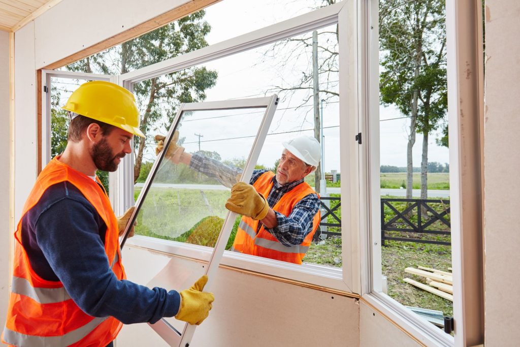 Two window installers installing a picture window in a bay window setup
