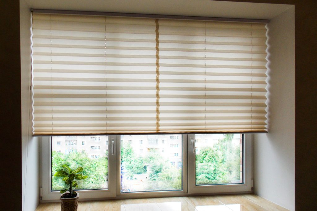 Pleated shades or honeycomb shades installed in front of casement windows drawn halfway