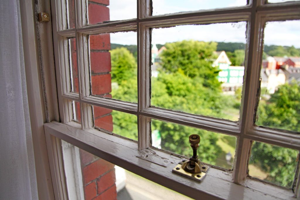 A pin lock securing a vintage single-hung window