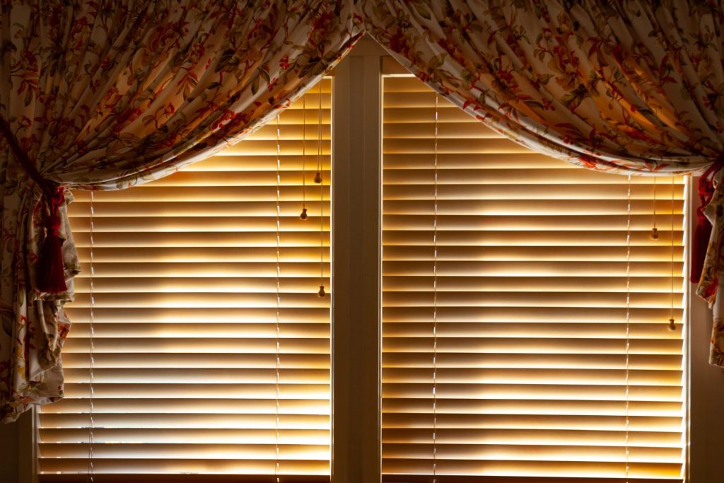 Venetian blinds blocking the sunlight with drawn curtains on the side