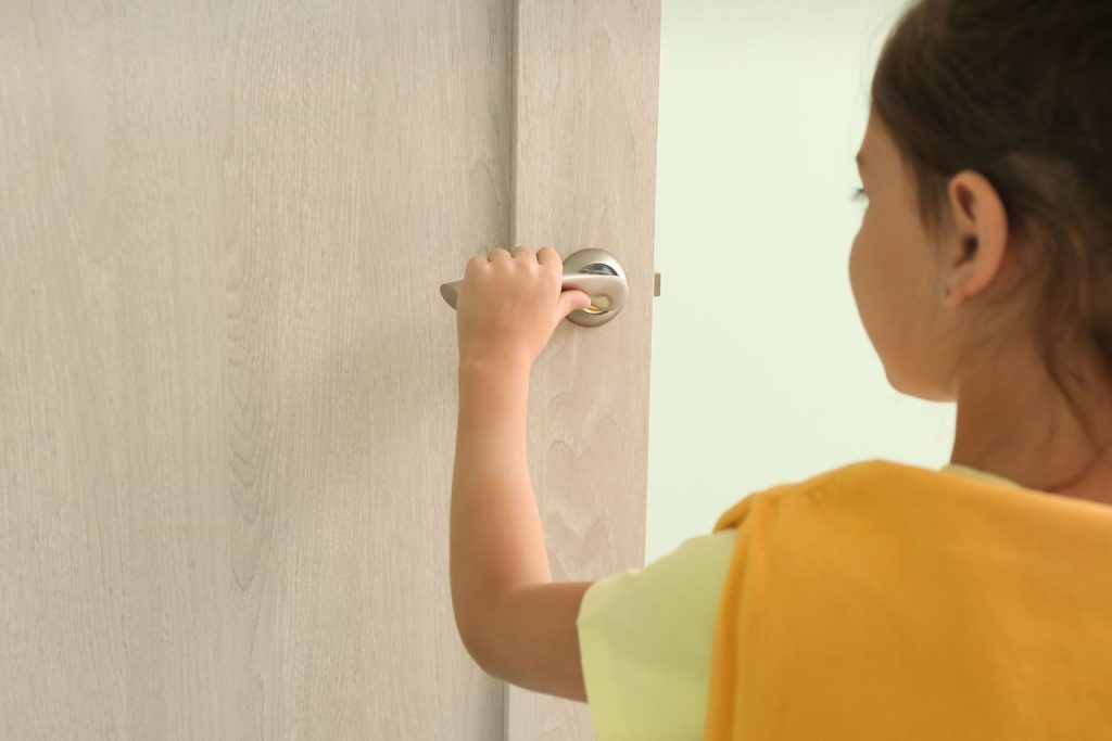 A toddler turning a door handle