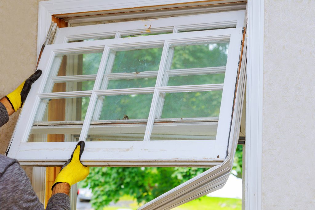 Window installer removing an old window sash