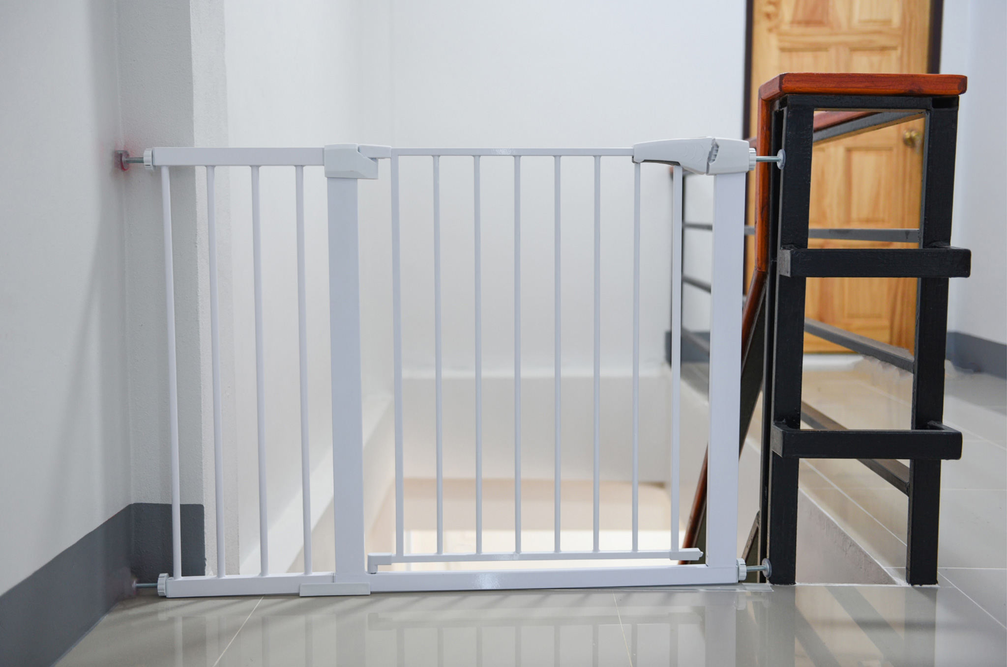 White baby-proofing gate at the top of a set of stairs