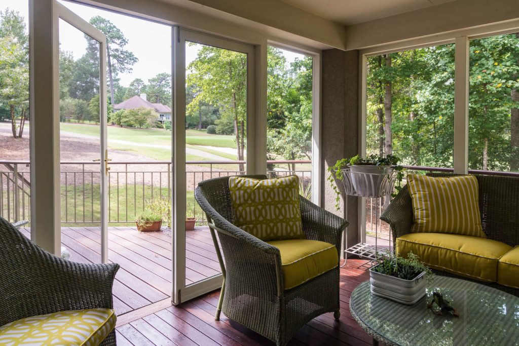Screen porch with French doors that lead to a deck with a view of a golf course