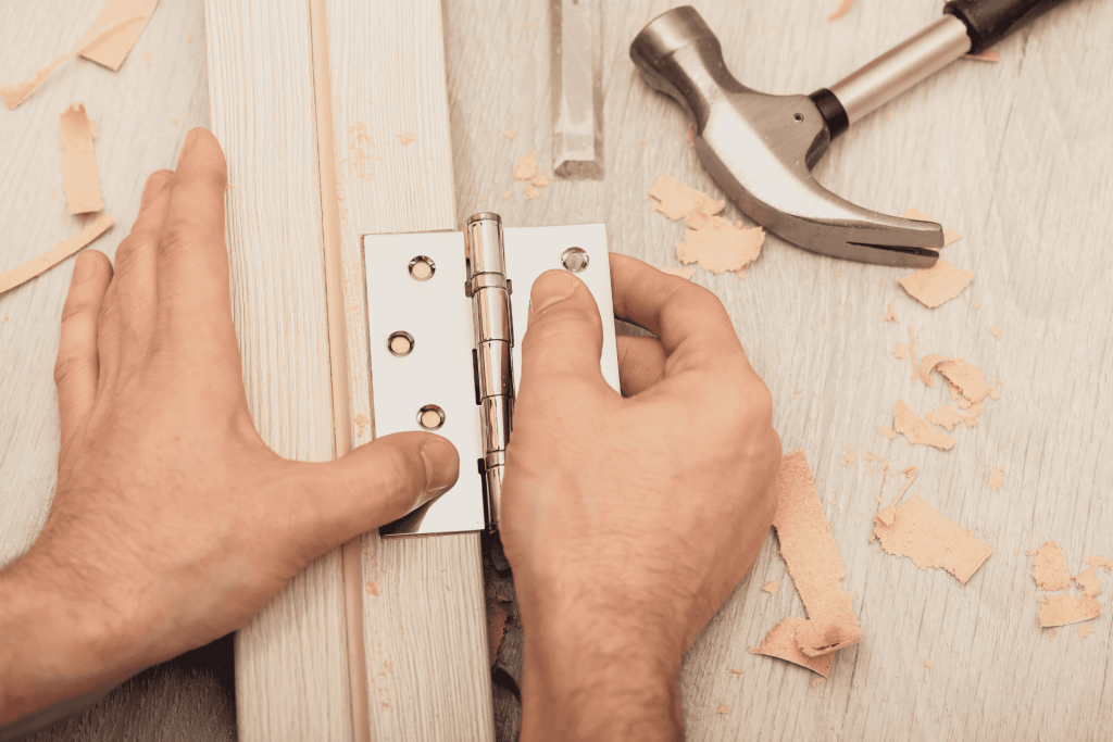 A worker installing a hinge on a door frame